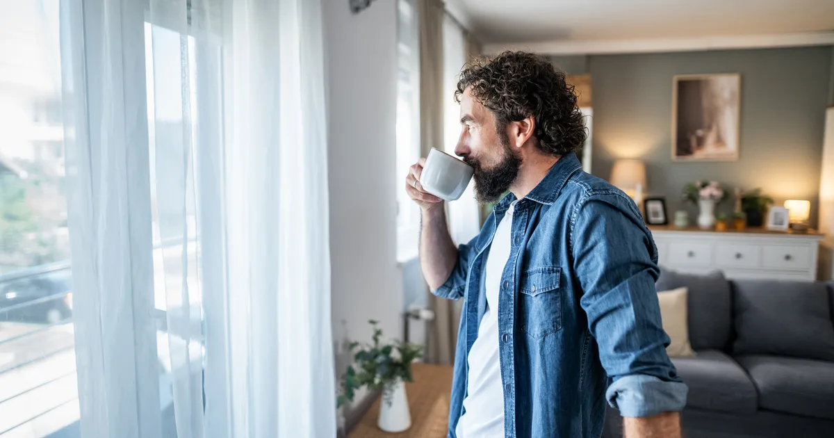 Man drinking coffee by a window in morning light