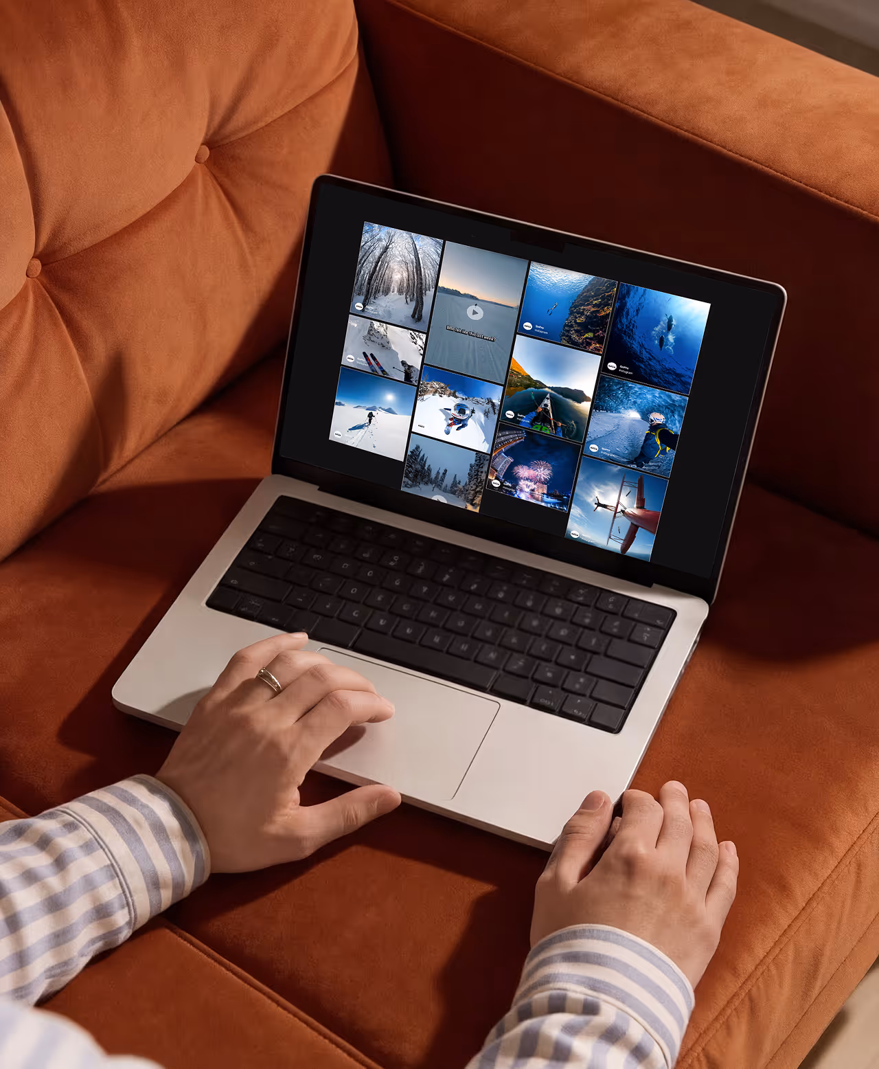 Person using a laptop on a brown couch displaying a grid of GoPro adventure social media posts on the screen.