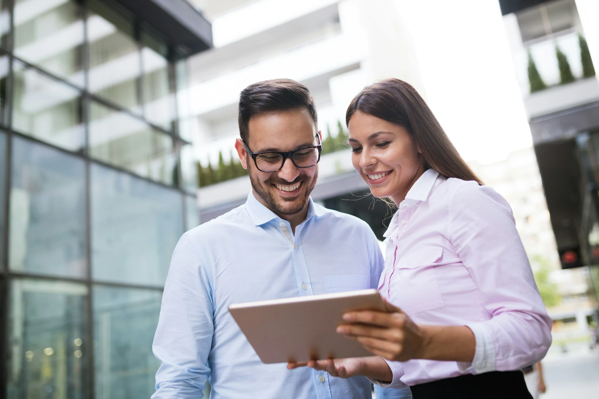 Ein Mann und eine Frau, lächeln und schauen gemeinsam auf ein Tablet und besprechen ihre Finanzen.
