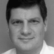 Black and white headshot of a man with short dark hair wearing a light shirt.
