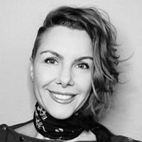 Black and white portrait of a smiling woman with short wavy hair wearing a patterned scarf.