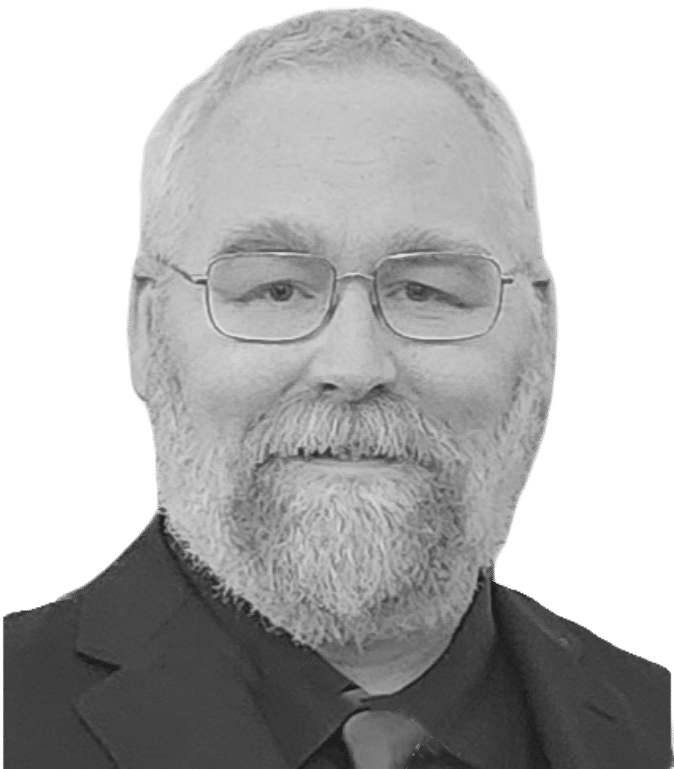 Man with glasses, gray beard, and mustache wearing a dark suit and tie, smiling slightly.