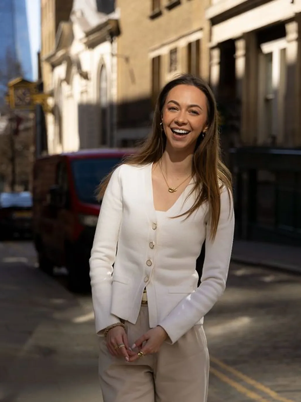 Cynthia de Gelder wearing a white cardigan and beige pants standing on a city street.