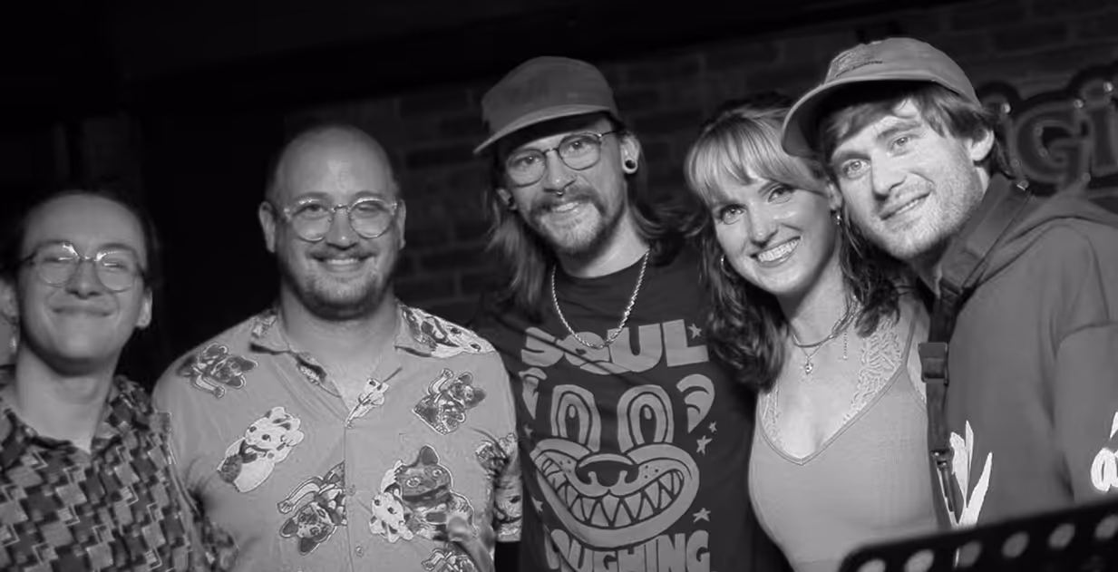5 band members huddled together in black and white photo.