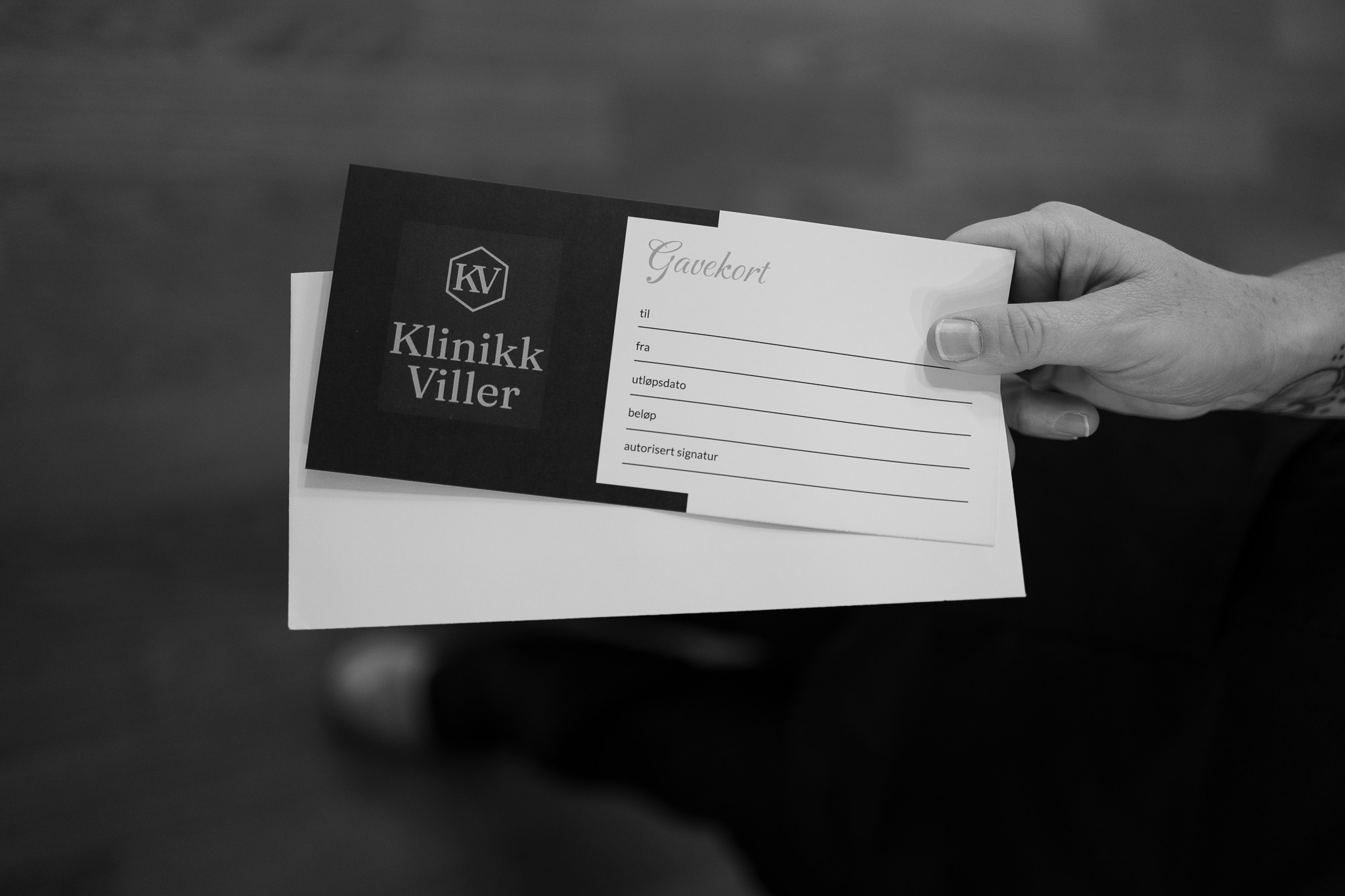 Hand holding a Klinikk Viller gift card and a white envelope.