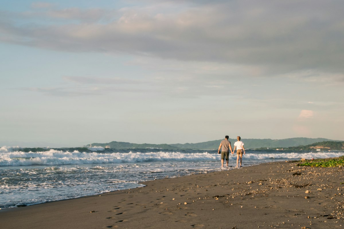 Casal caminhando à beira-mar