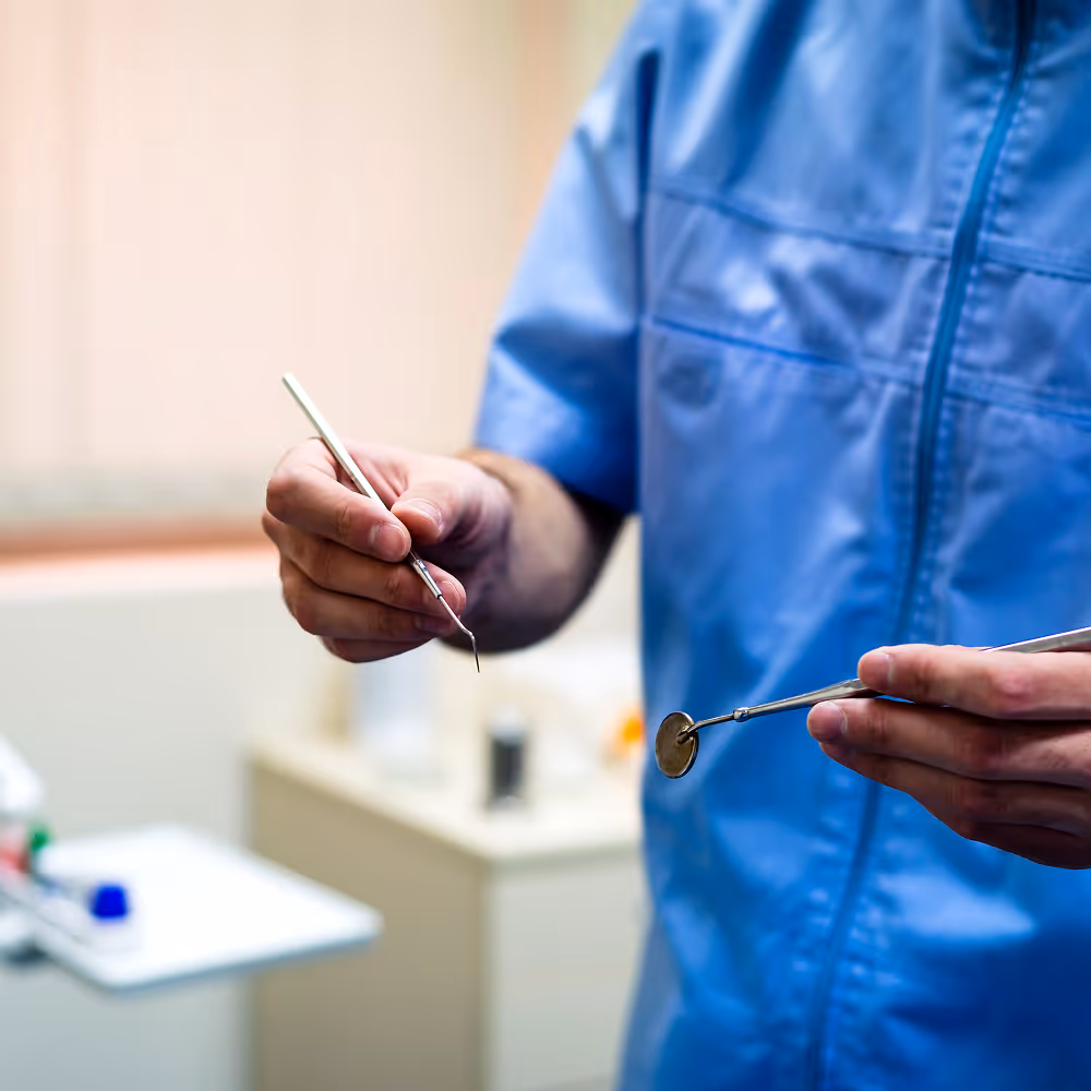 Dentist placing Arestin antibiotic microspheres into gum pockets after scaling and root planing