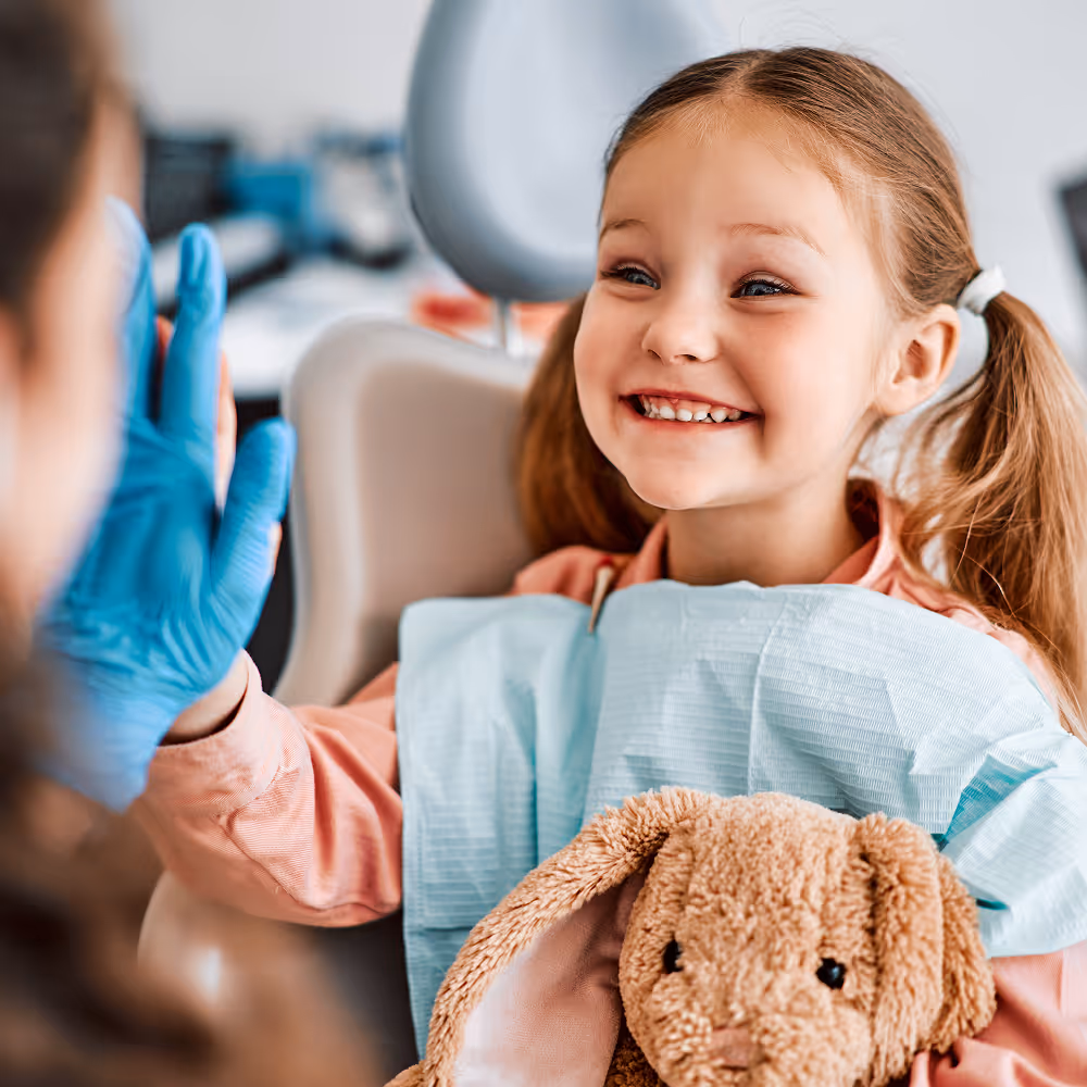Child smiling during a dental visit with friendly staff