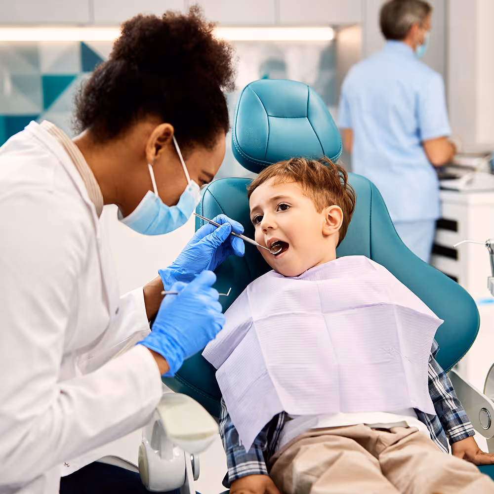 Pediatric dentist examining a child patient gently