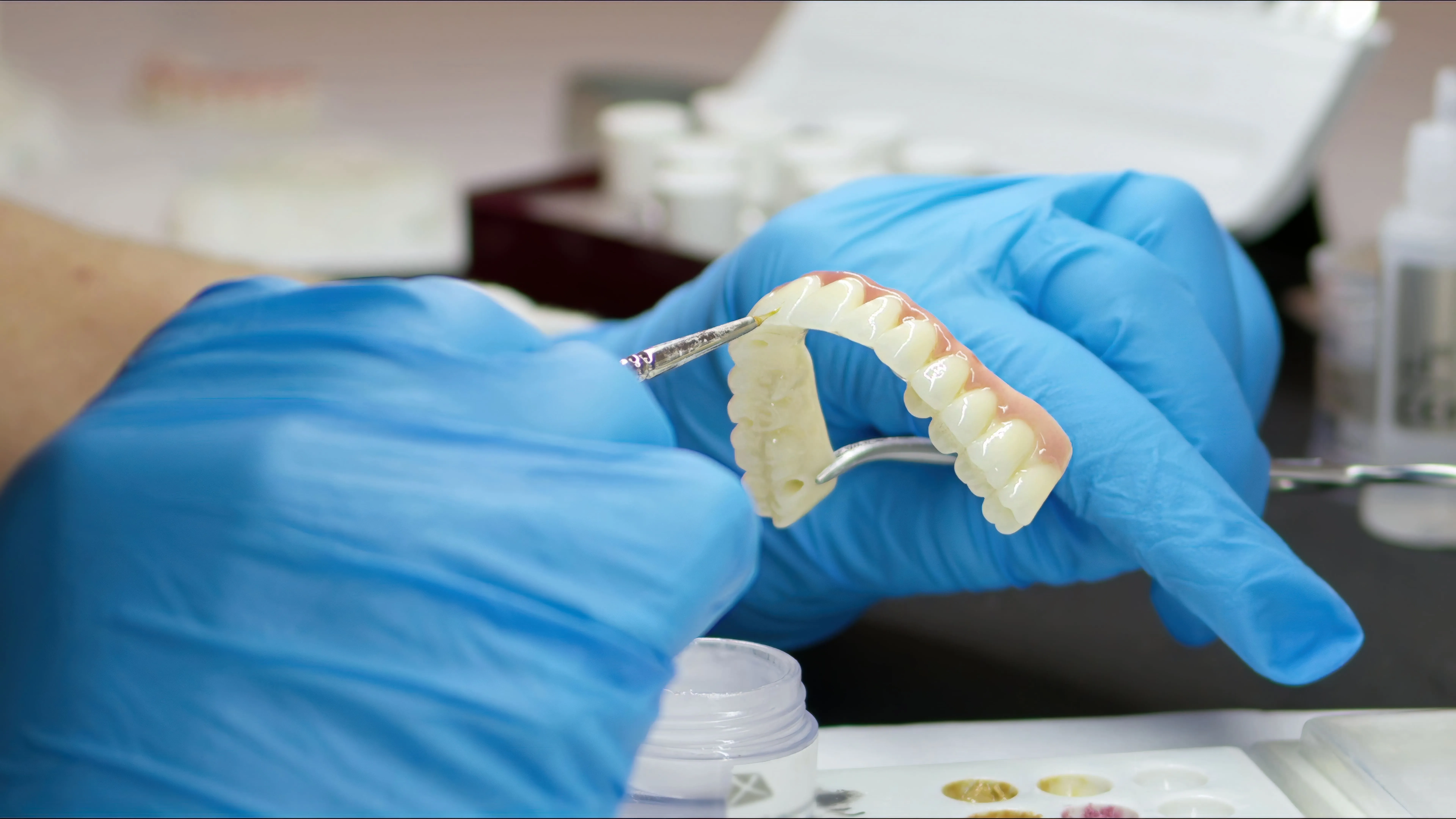 Dental professional holding a full-arch implant bridge near Nutley, NJ