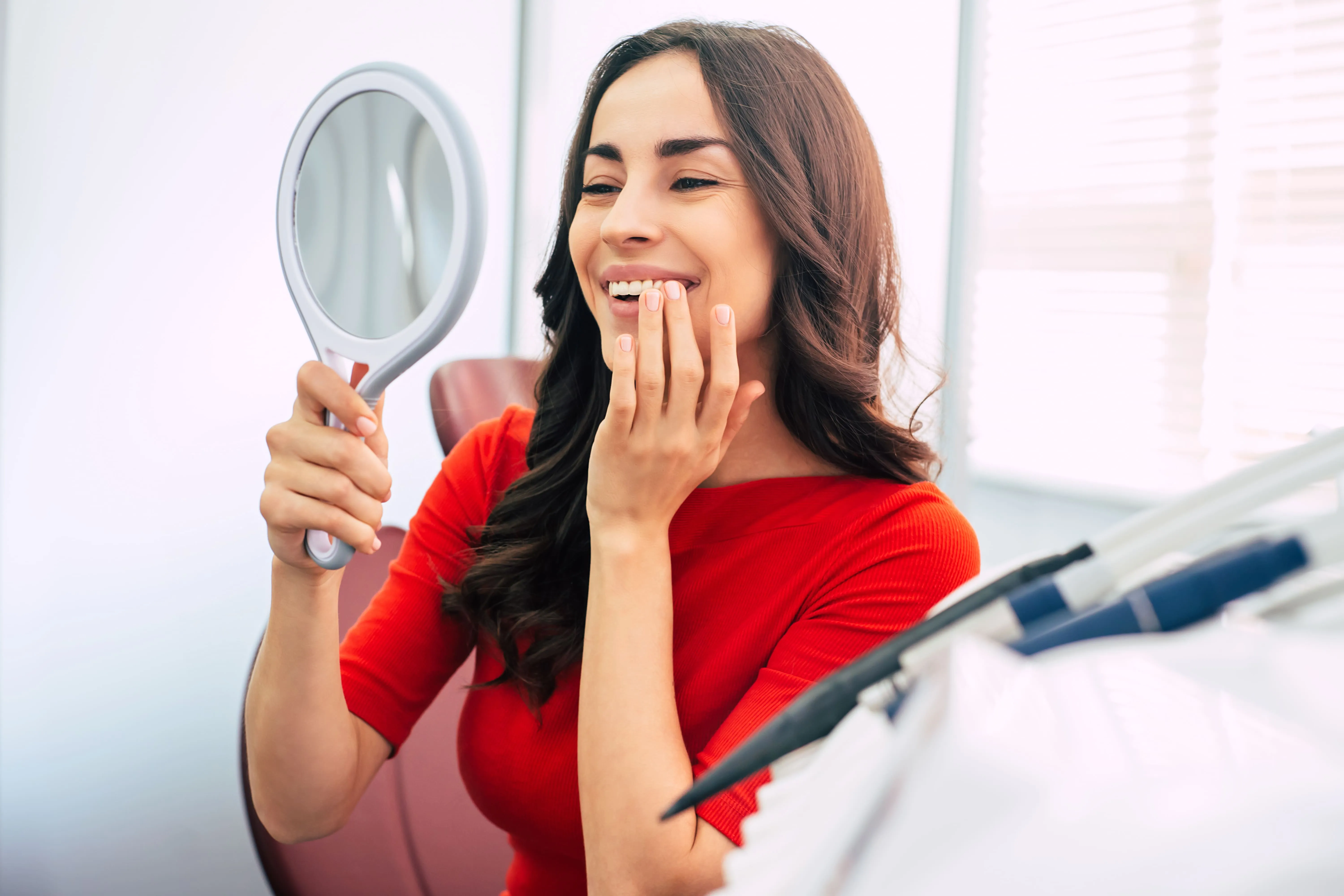 Patient checking her smile in a mirror after restorative dental care near Wayne, NJ