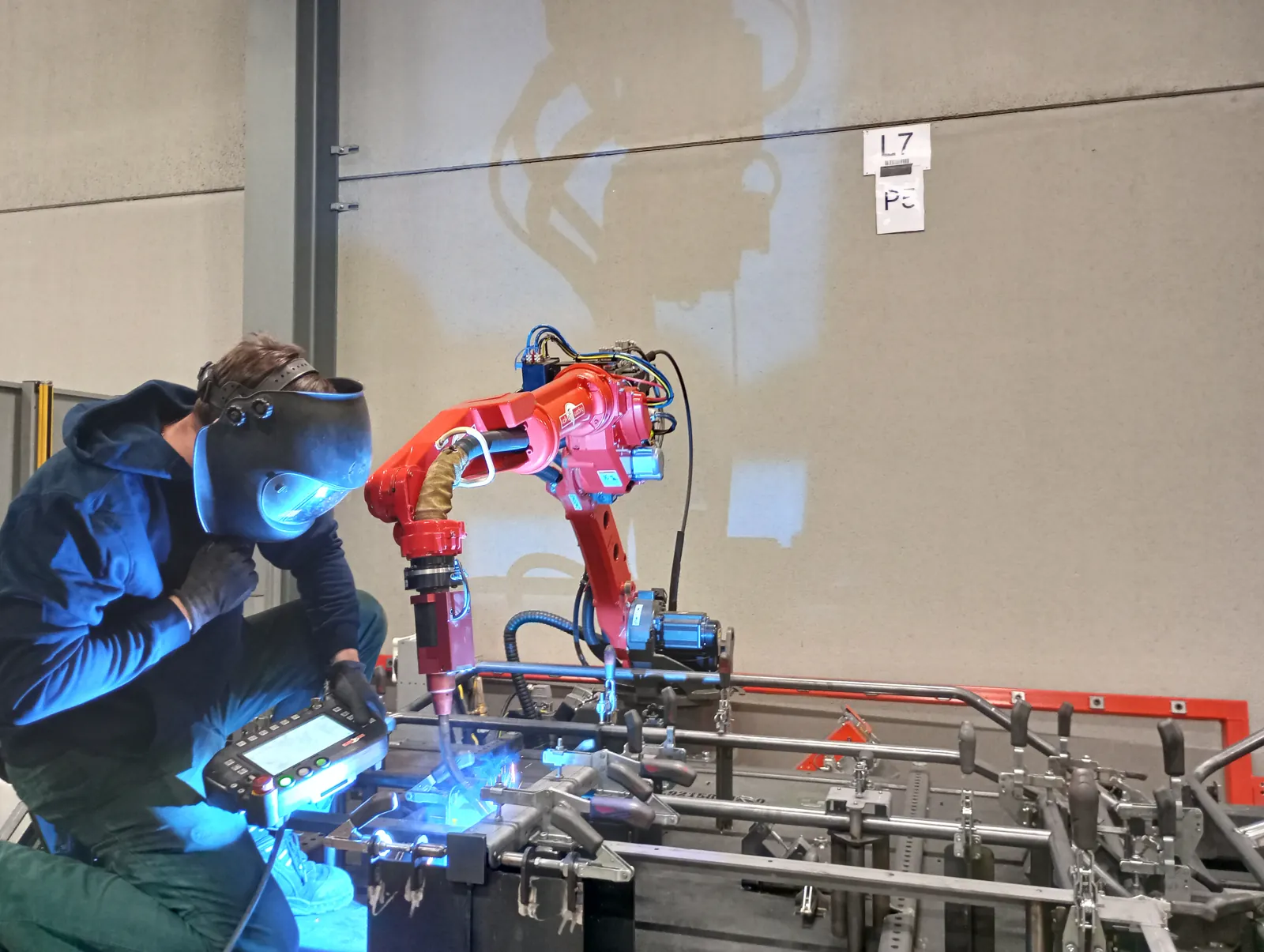 Lasser werkt naast een lasrobot bij Allemeersch