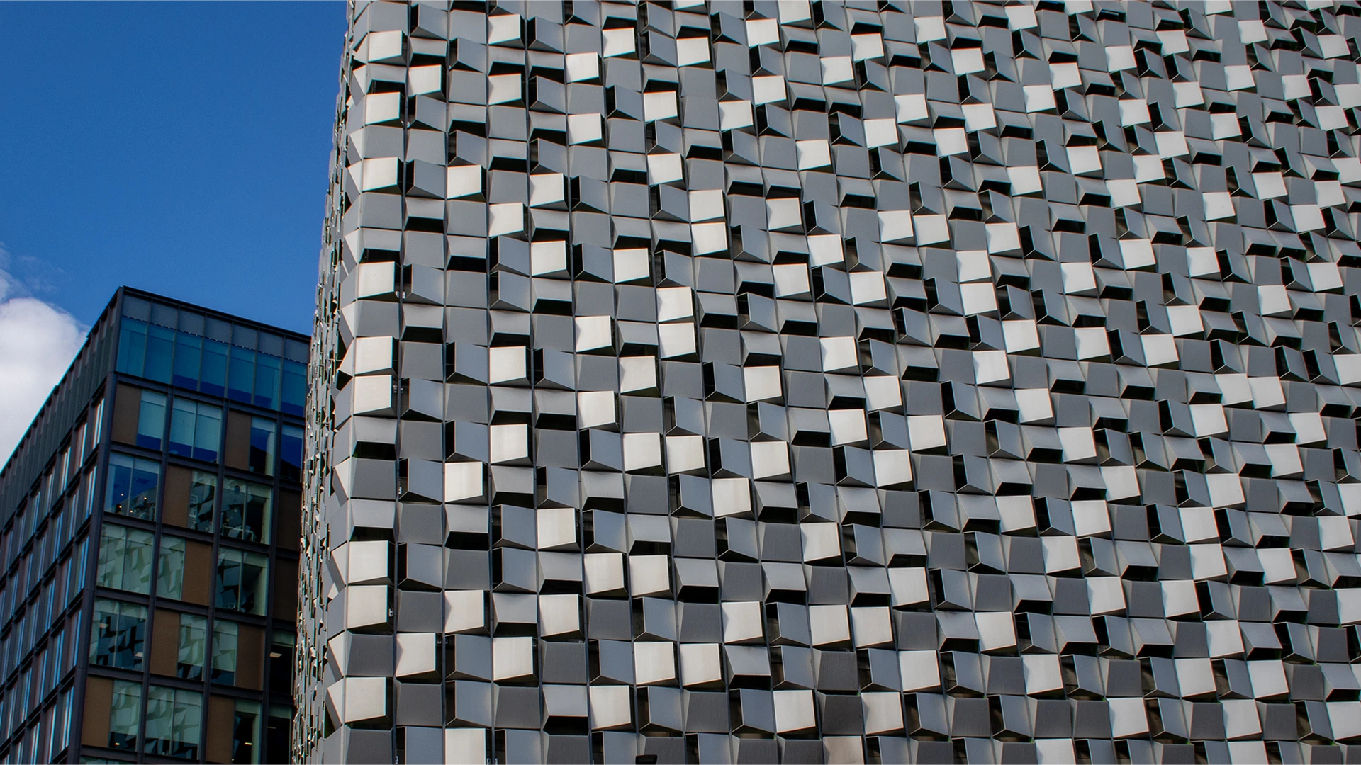 The Cheesegrater's anodised aluminium façade curving away beside a neighbouring glazed office in Sheffield