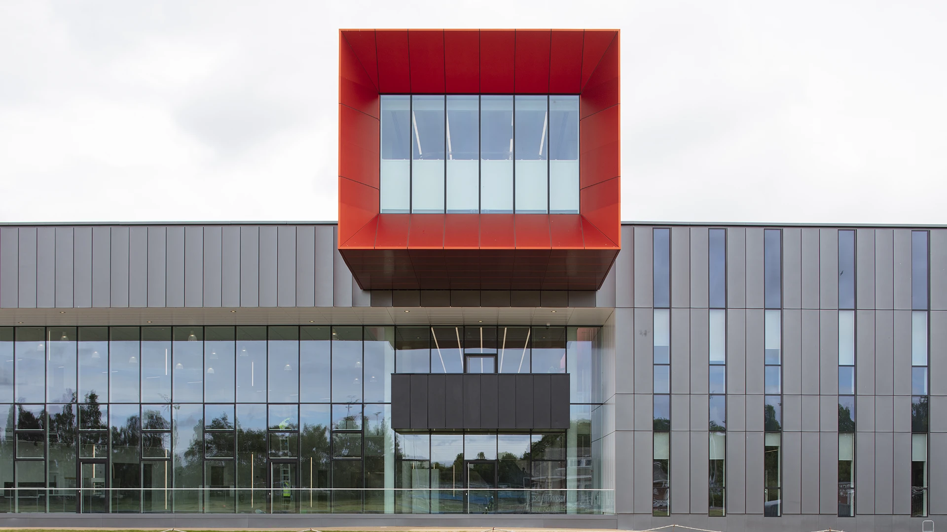 Looking up at the underside of the red UnAtex anodised aluminium cantilever against the curved grey rainscreen