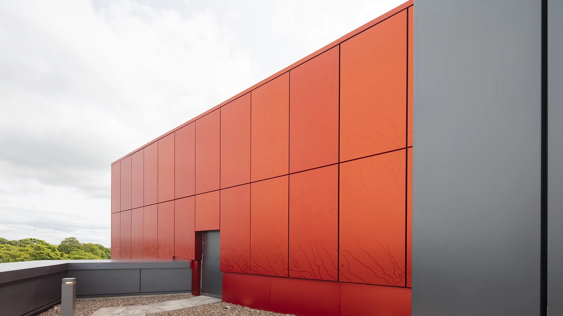 Close view of the red on red UnAtex anodised aluminium rainscreen panels, showing contrasting gloss levels across the panel grid