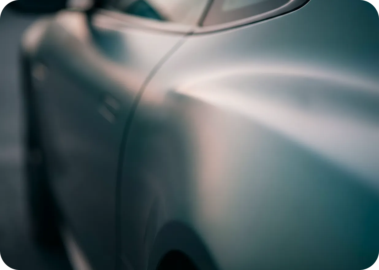 Close-up view of a sleek silver car's side panel and rear wheel area.
