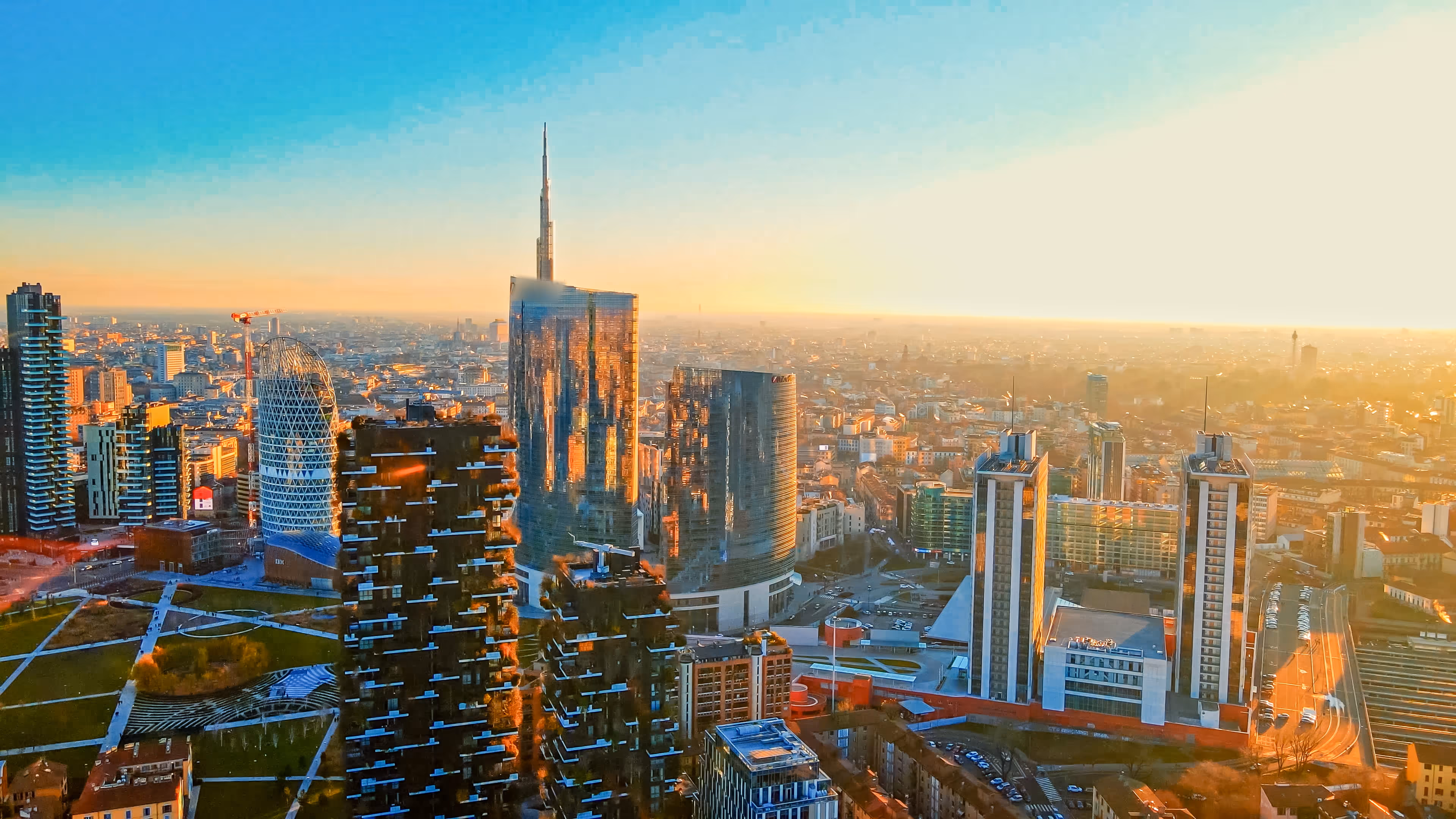 Sunset cityscape of Milan with modern skyscrapers, including the UniCredit Tower and vertical forest buildings.