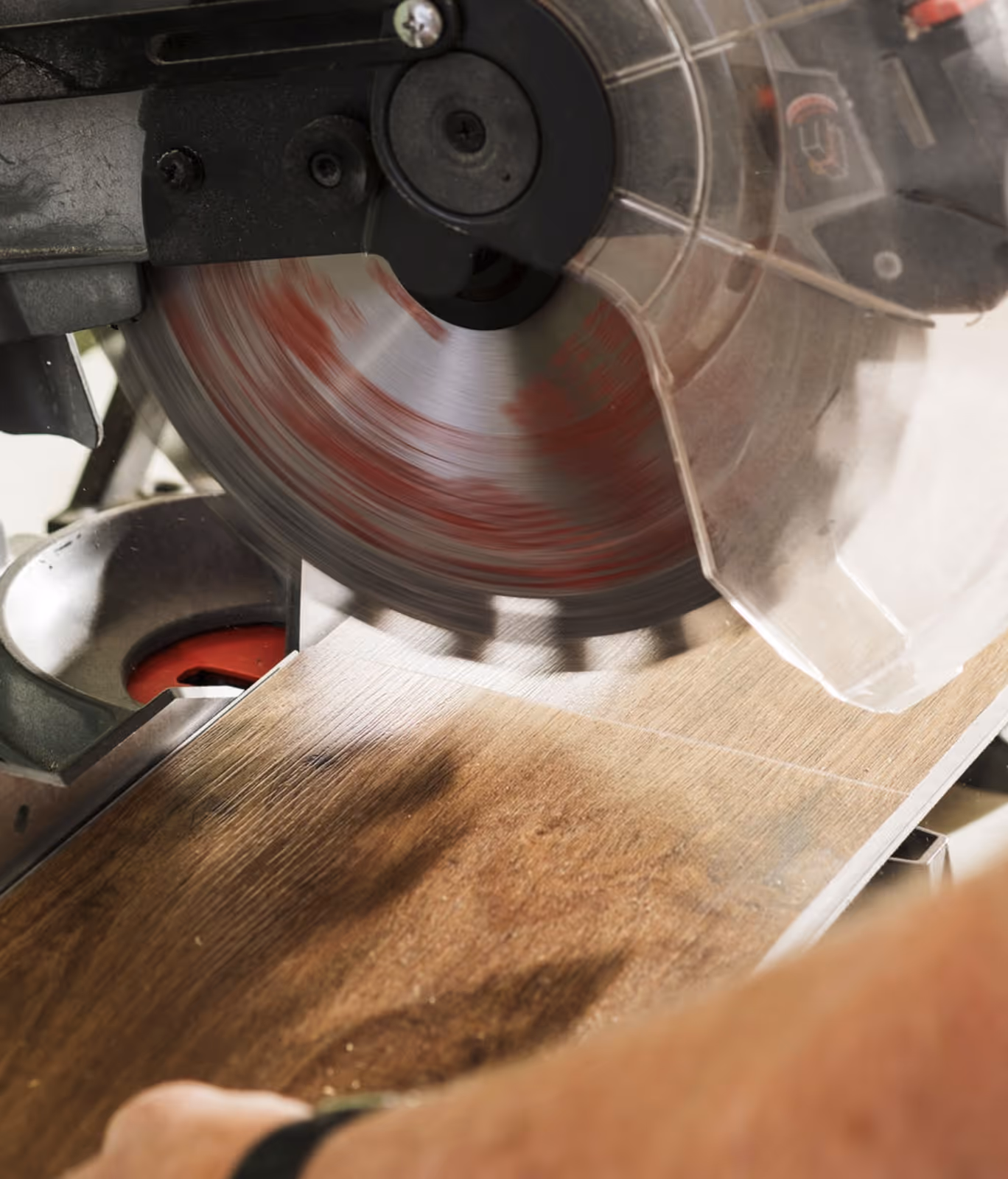 Close-up of a circular saw cutting into a wooden plank with a protective guard visible.