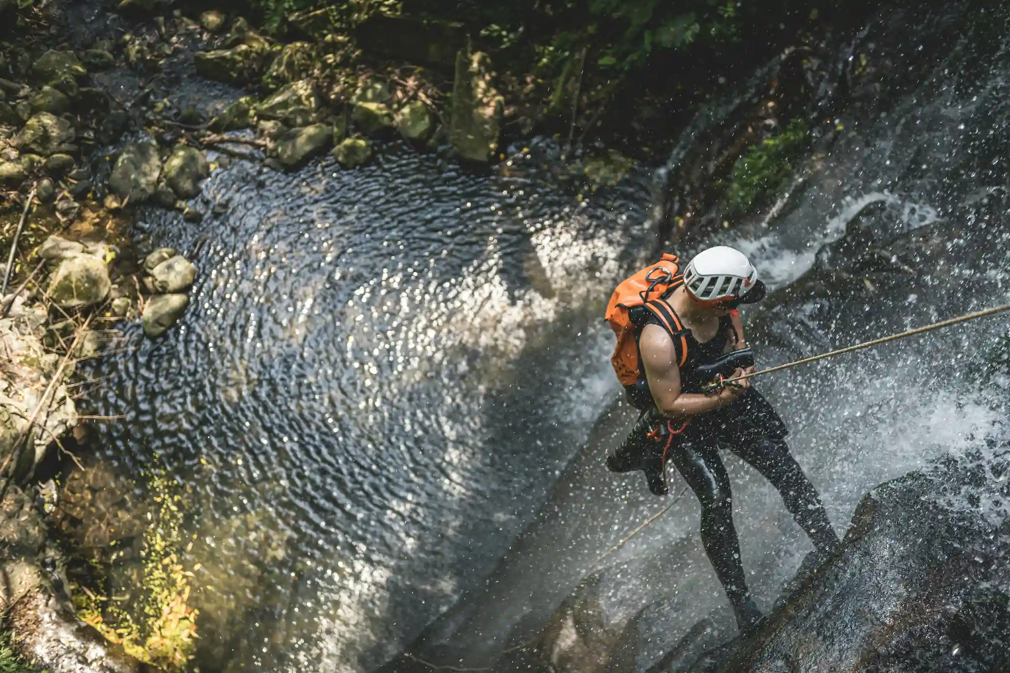 A man rappelling down a canyon wall during a canyoning adventure.