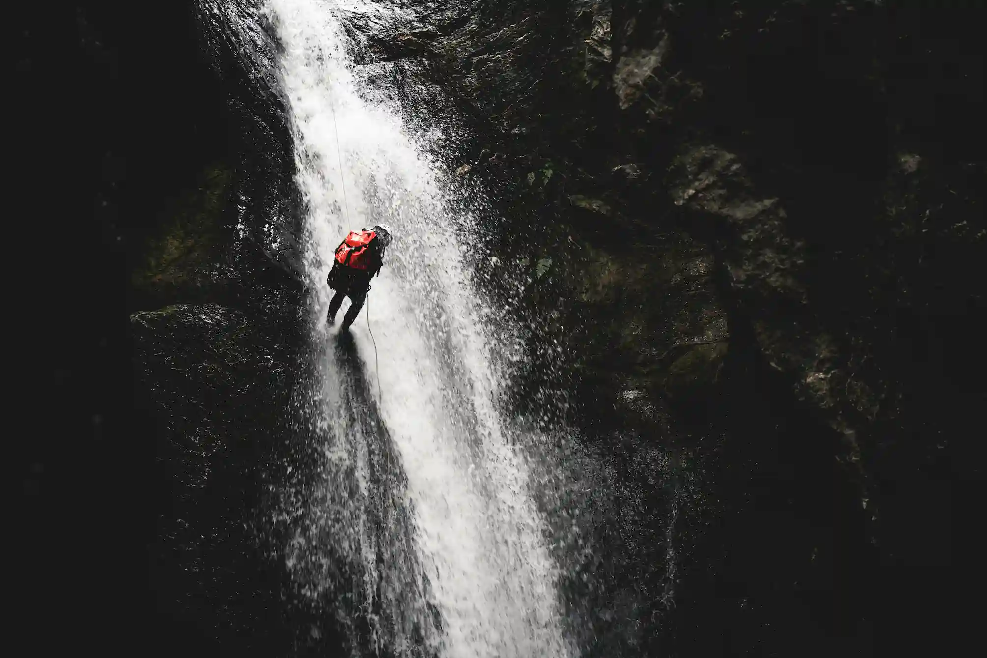 A man descending a waterfall during a canyoning adventure