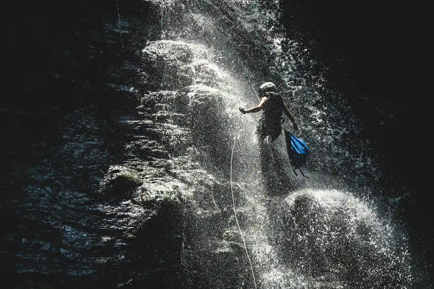 Canyoning easy slide with rope on waterfall