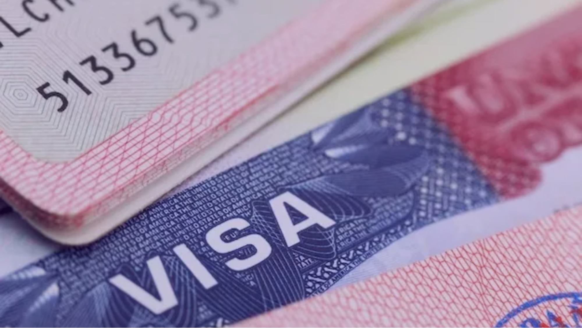 Close-up of overlapping U.S. visa pages in red and blue, with visible text and a security pattern, conveying formality and importance.