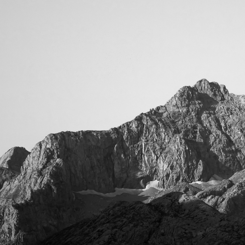 Black and white photo of rugged mountain peaks with rocky textures under a clear sky.