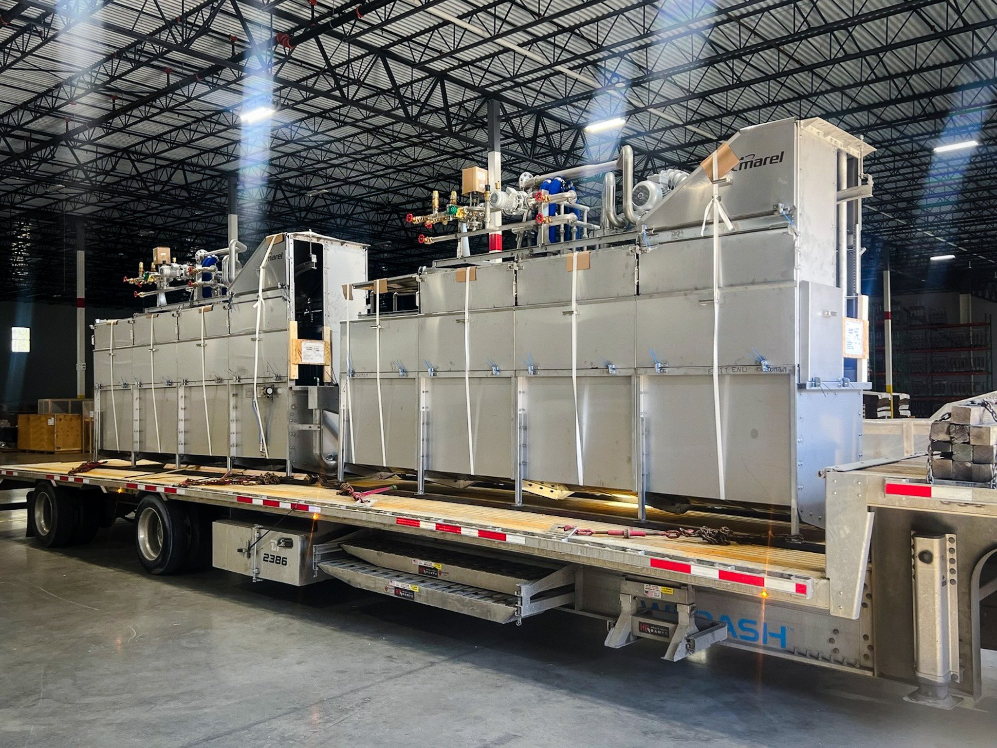 Industrial equipment loaded on a step deck trailer inside a manufacturing plant