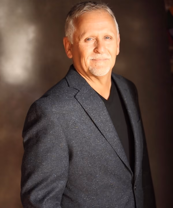 Professional portrait of Dr. Dannelly wearing a blazer and smiling in a studio setting.