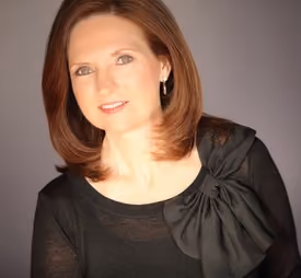 Professional portrait of Melissa Gibbs smiling in a studio setting.
