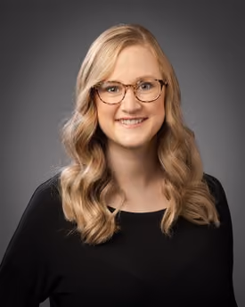 Professional portrait of Emily Ann Stacy smiling in a studio setting.