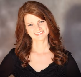 Professional portrait of Kristi King smiling in a studio setting.