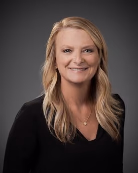 Professional portrait of April Dawn Baldwin smiling in a studio setting.