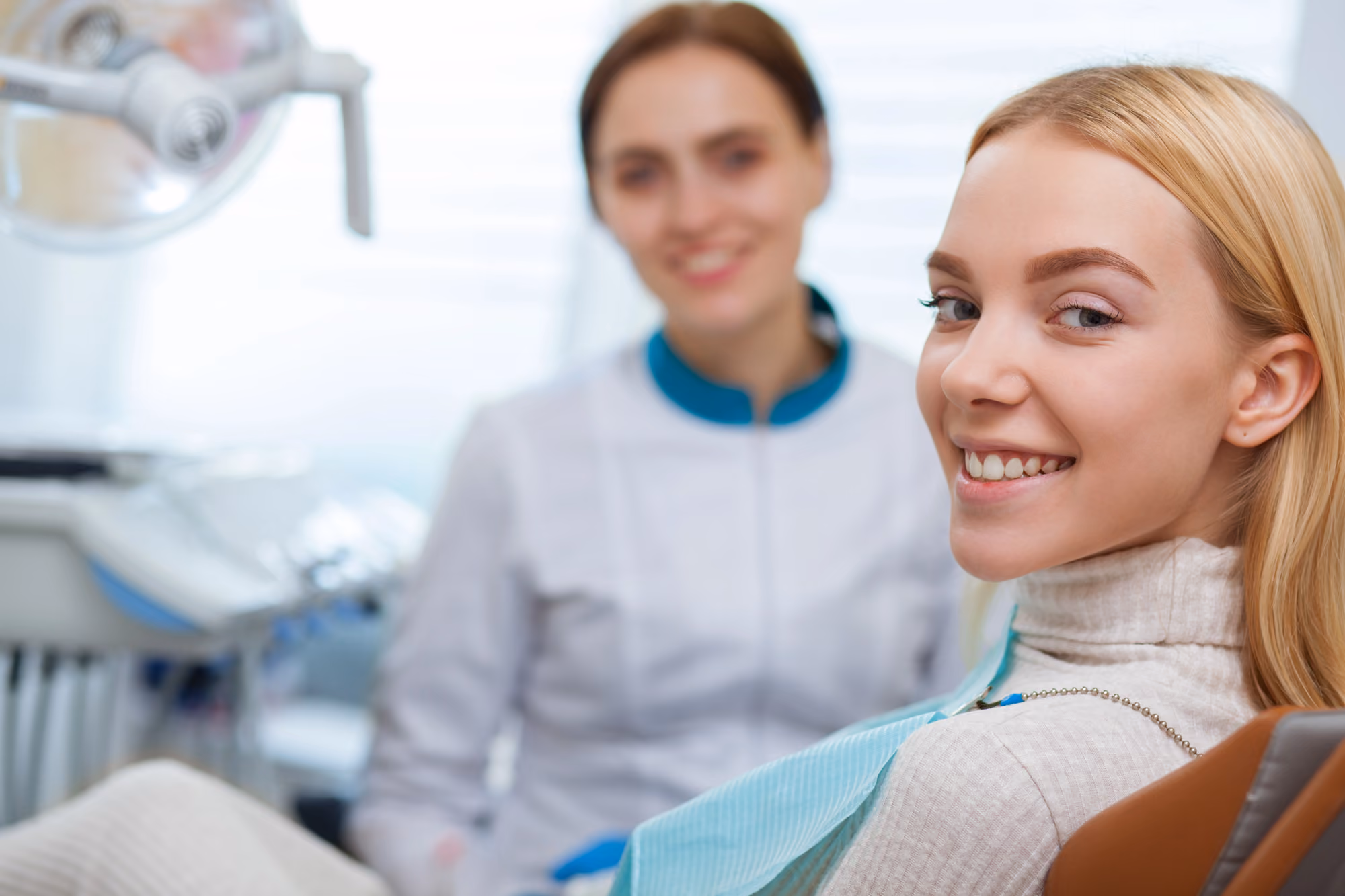 Smiling patient seated in a dental chair during a consultation with a dental professional.