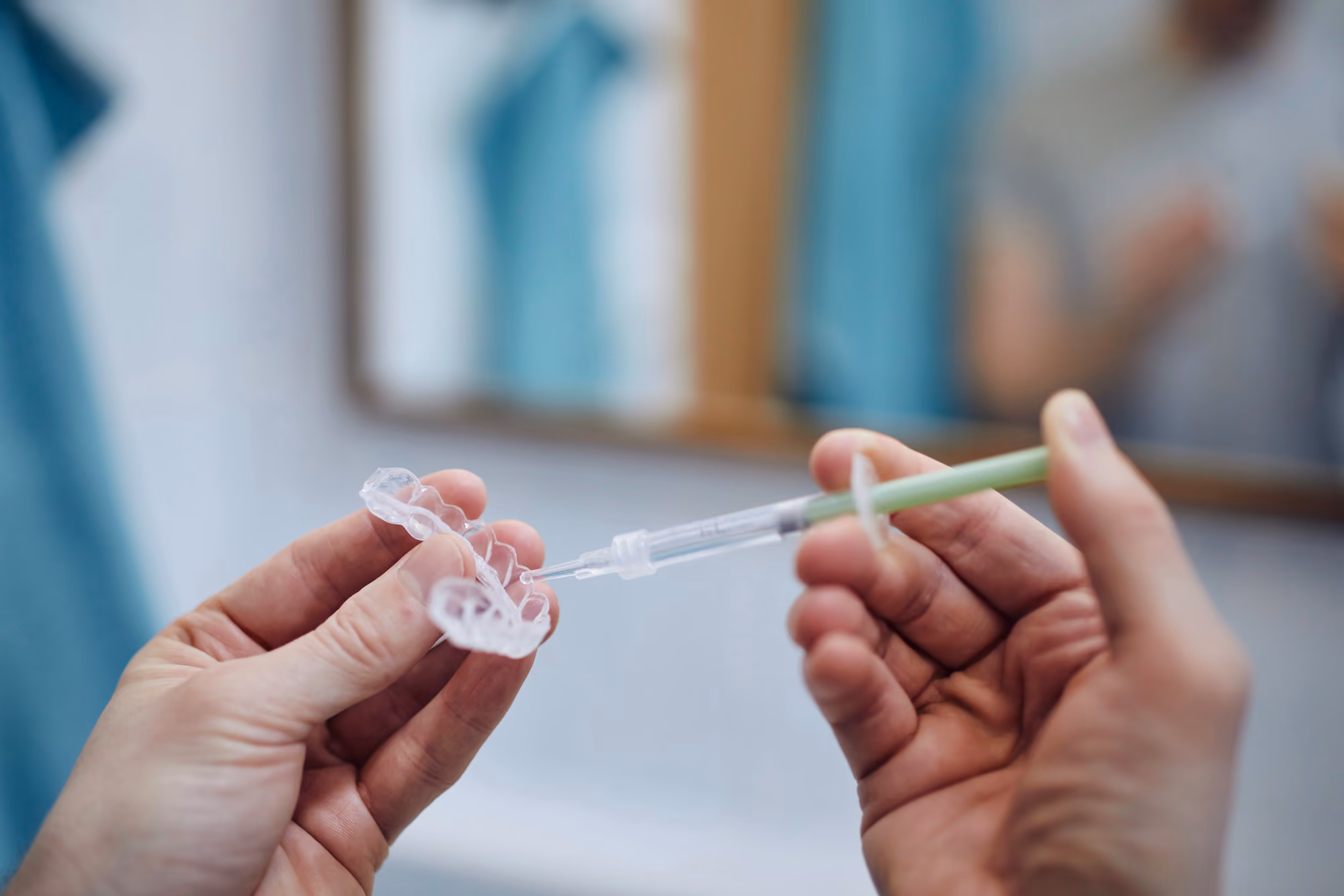 Close-up of hands cleaning a clear aligner tray with a toothbrush.