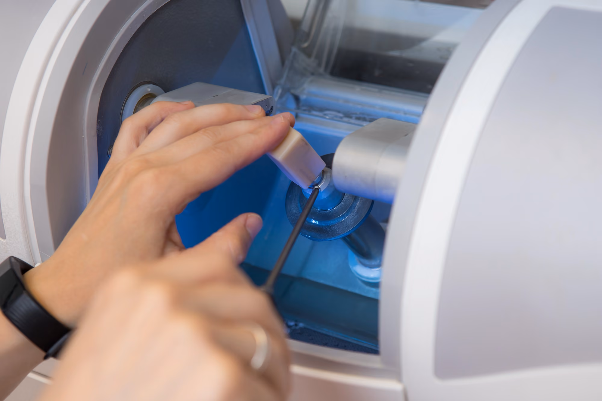 Dental technician operating a chairside milling machine to fabricate a dental restoration.