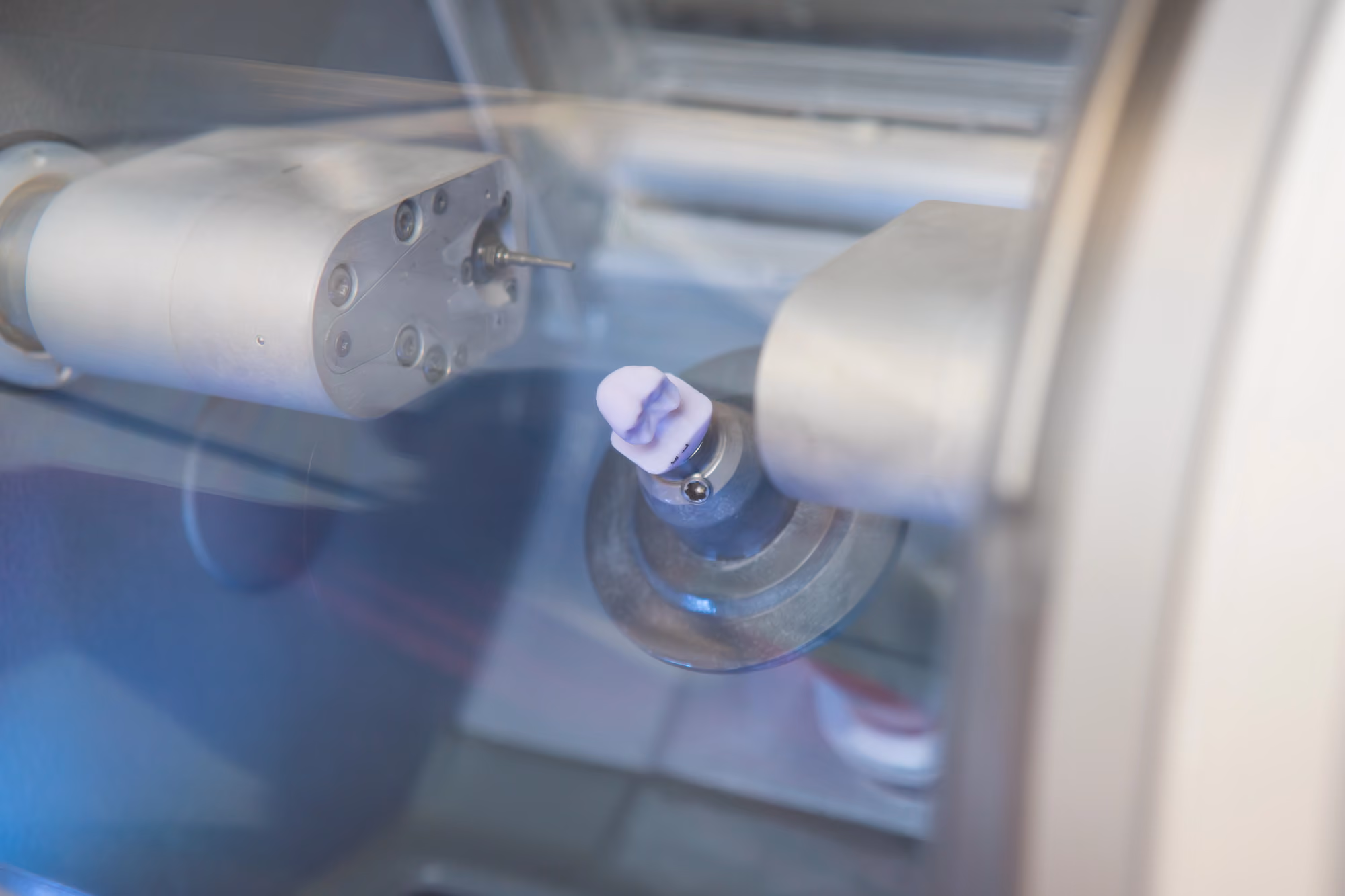 Close-up of a ceramic dental crown being milled by CAD/CAM technology.