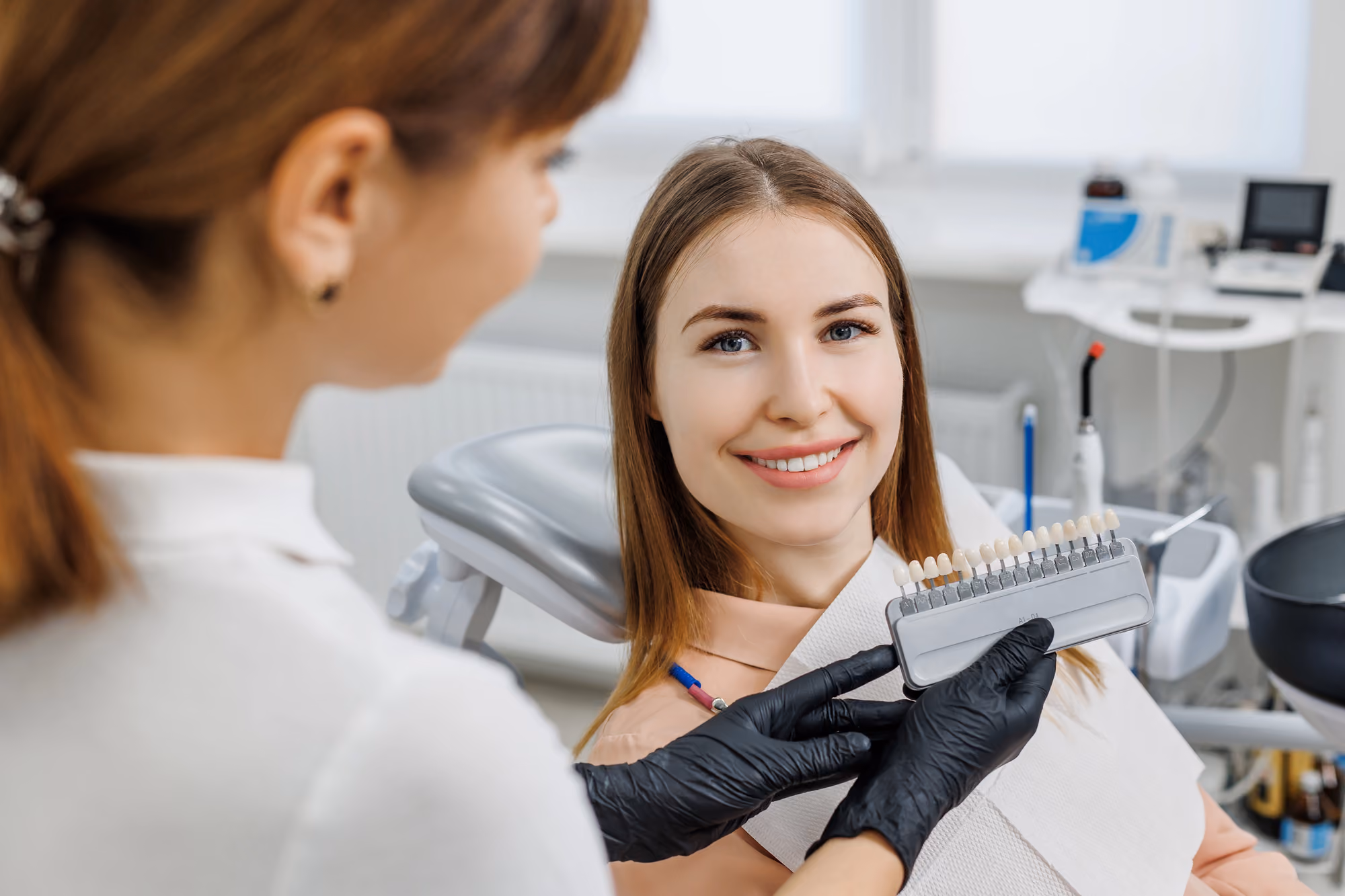 Patient comparing tooth shade guide options during a cosmetic dental consultation.