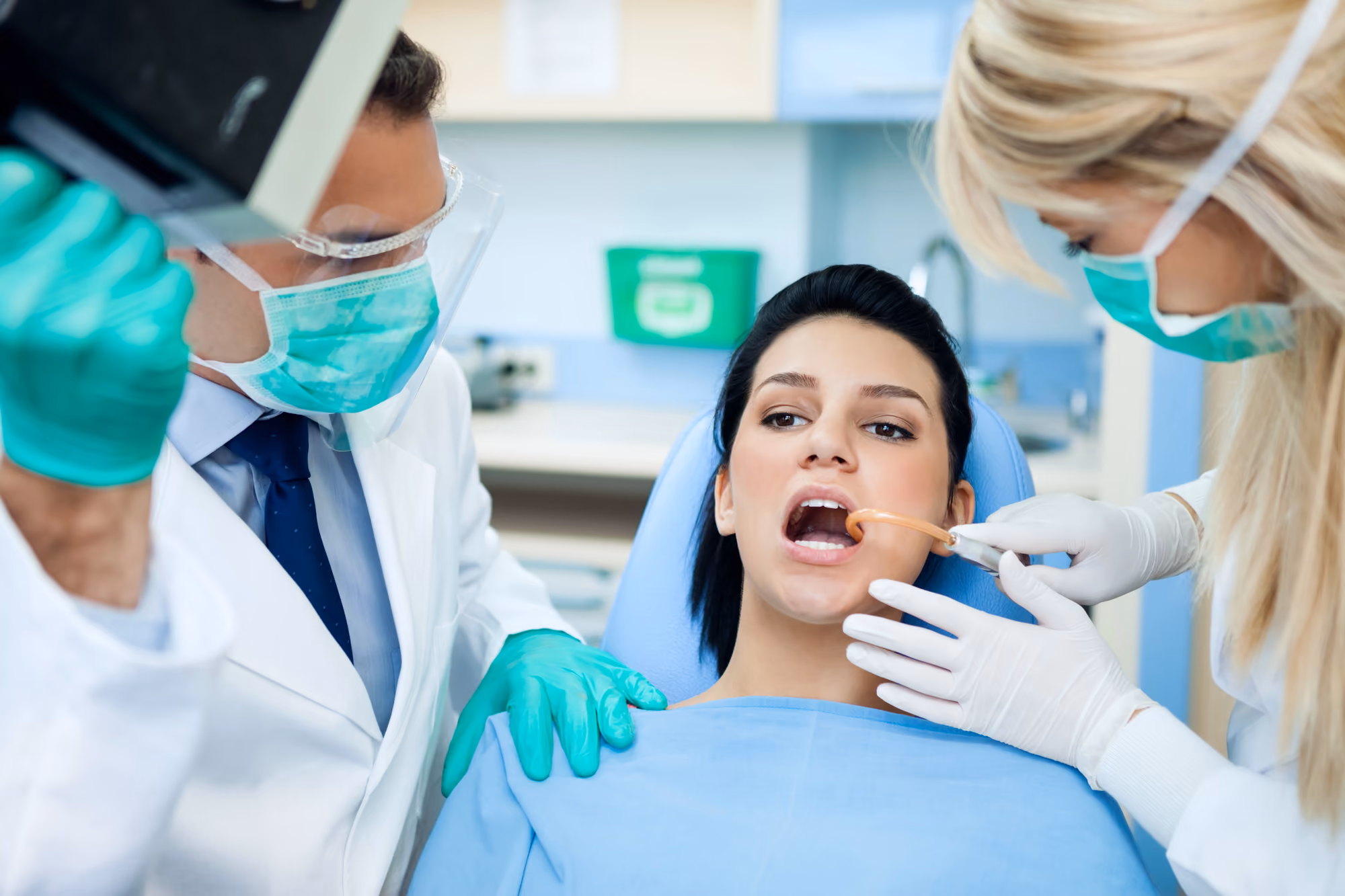 Dental team applying whitening gel during an in-office cosmetic whitening treatment.