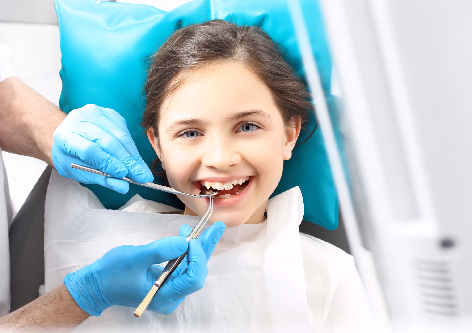 Child smiling while practicing flossing during a dental appointment.