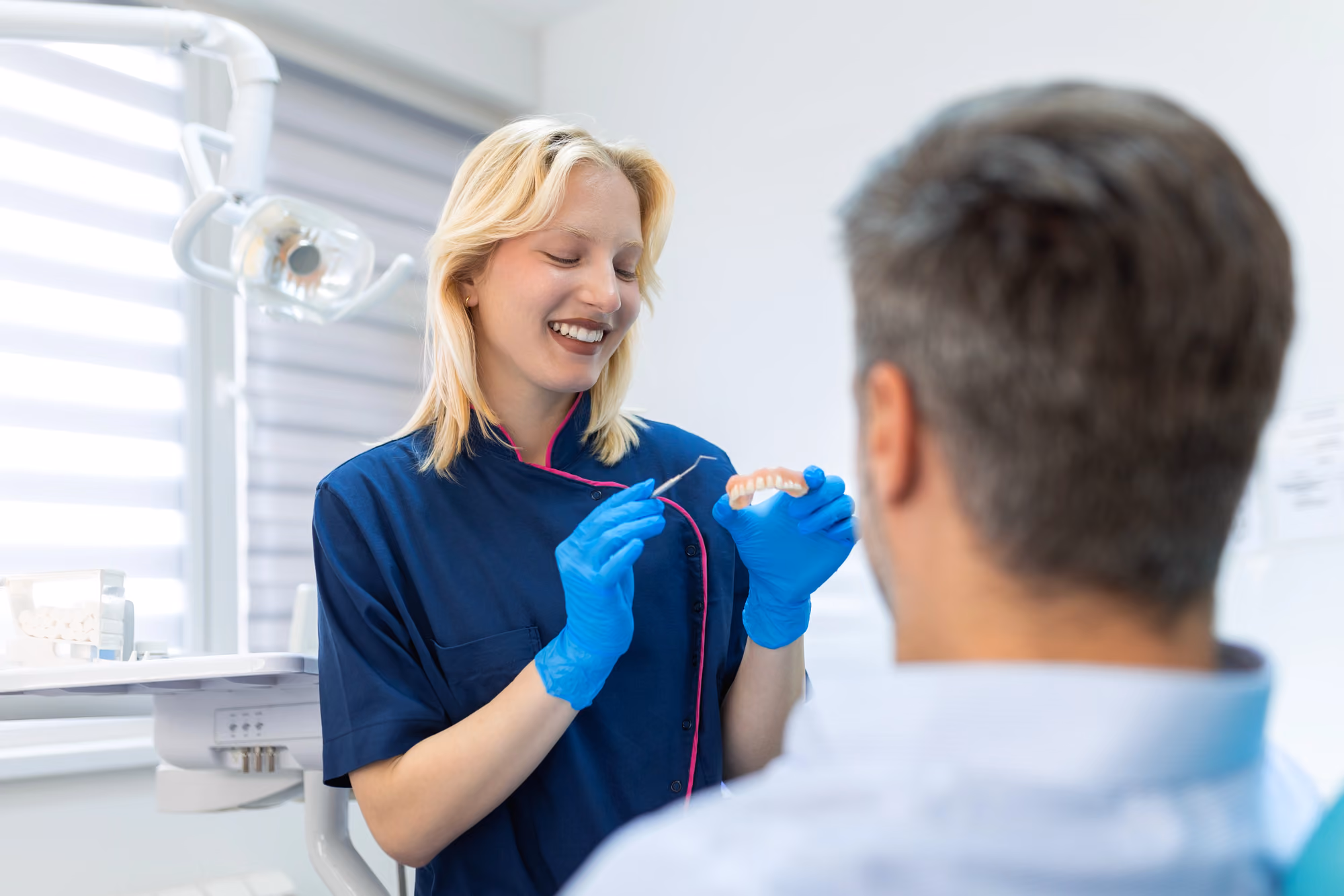 Dental hygienist demonstrating flossing technique using a dental model during patient education.