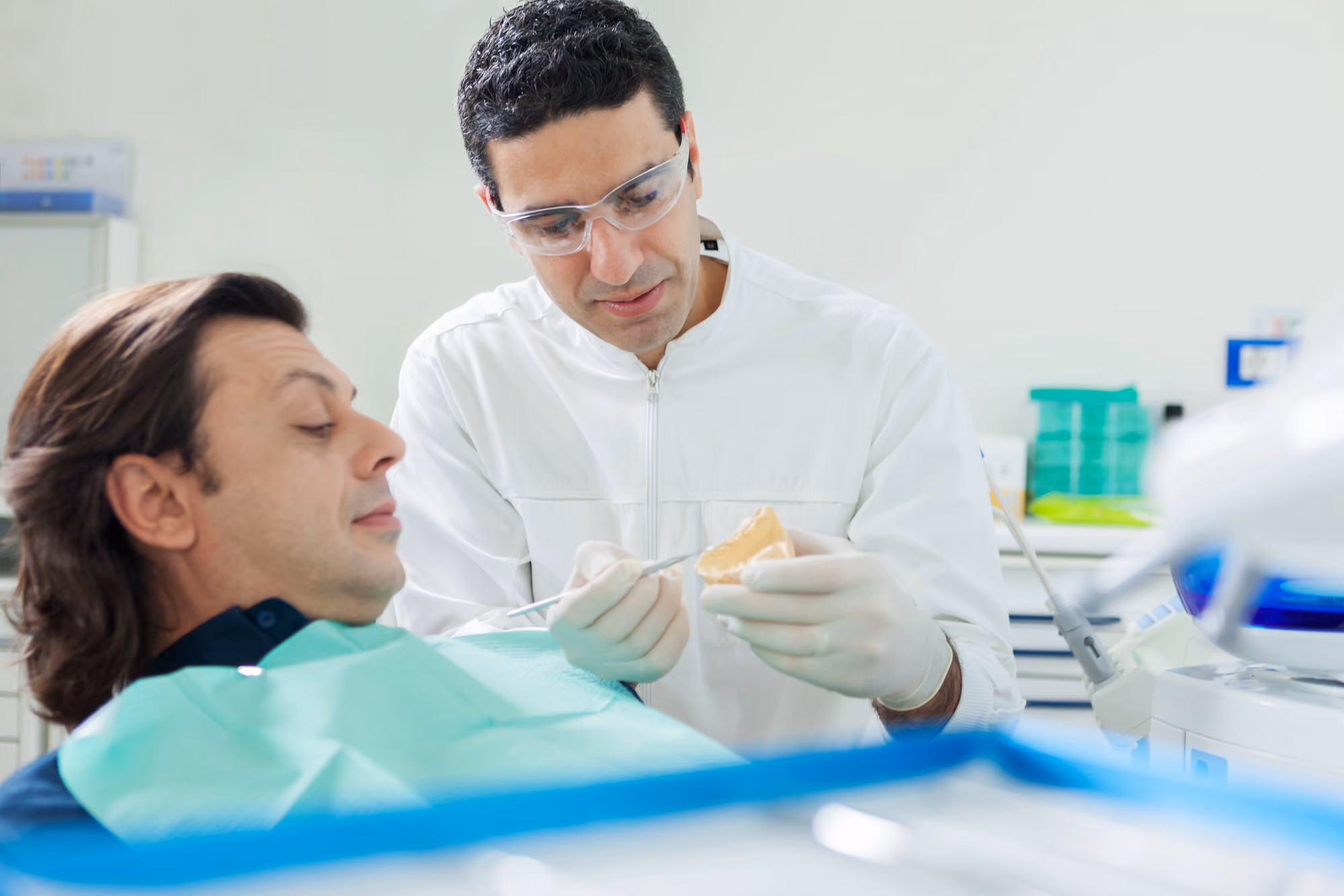 Dentist evaluating a prosthetic tooth restoration with a patient during consultation.
