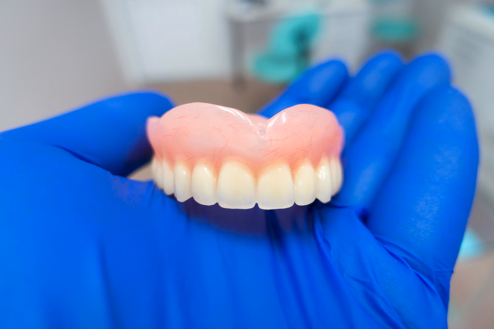 Dental professional holding dental prosthetic teeth components for evaluation or demonstration.