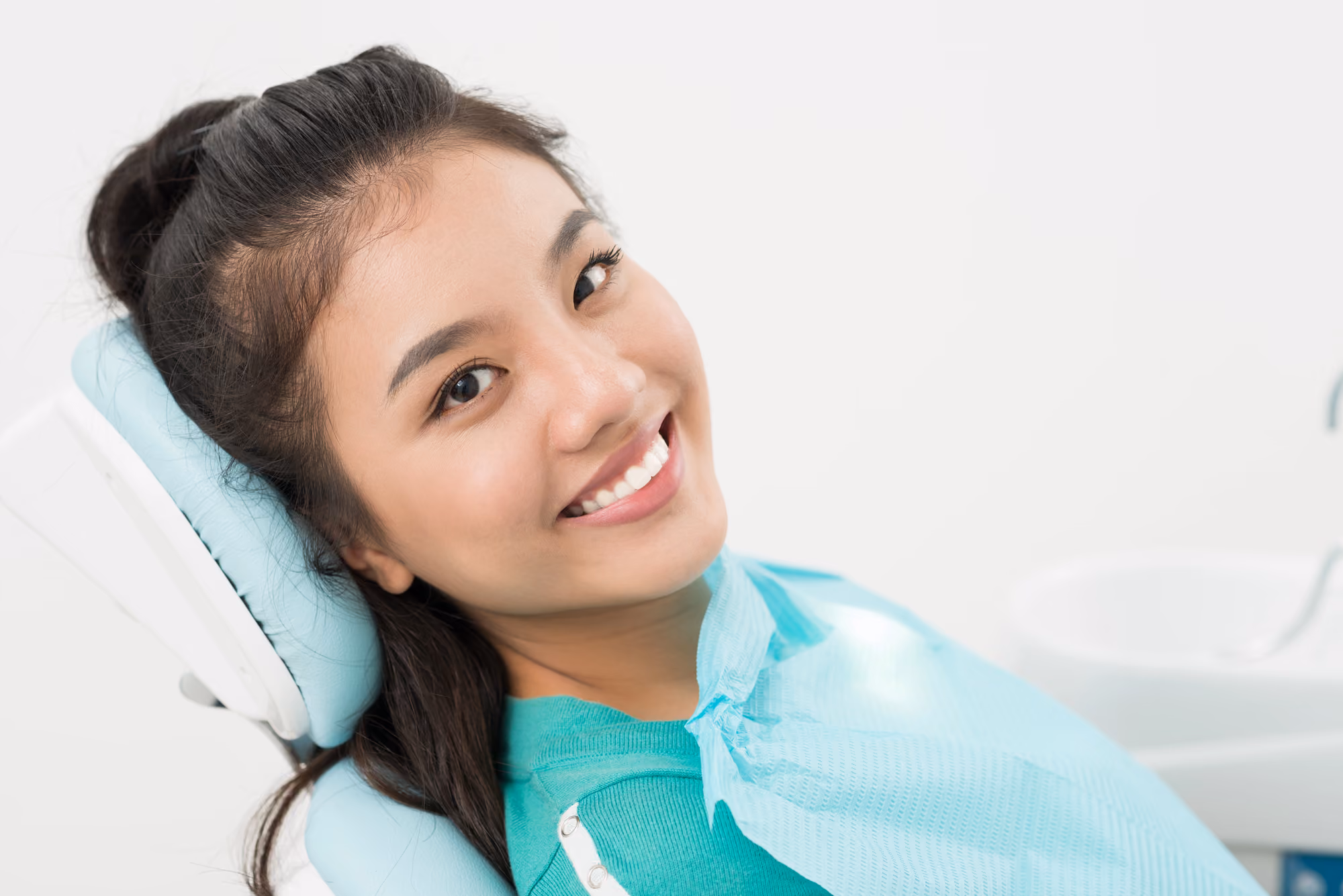 Young female patient smiling comfortably while seated in a dental chair.