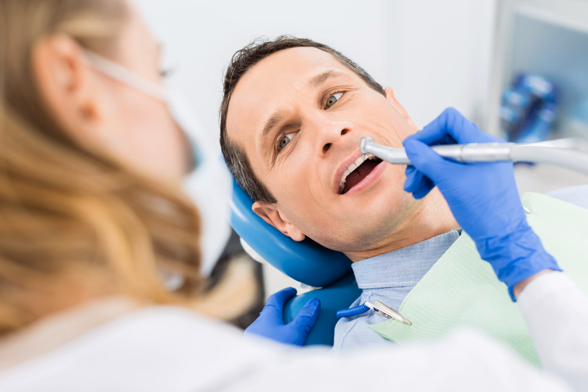 Dental hygienist performing a professional teeth cleaning on a patient.