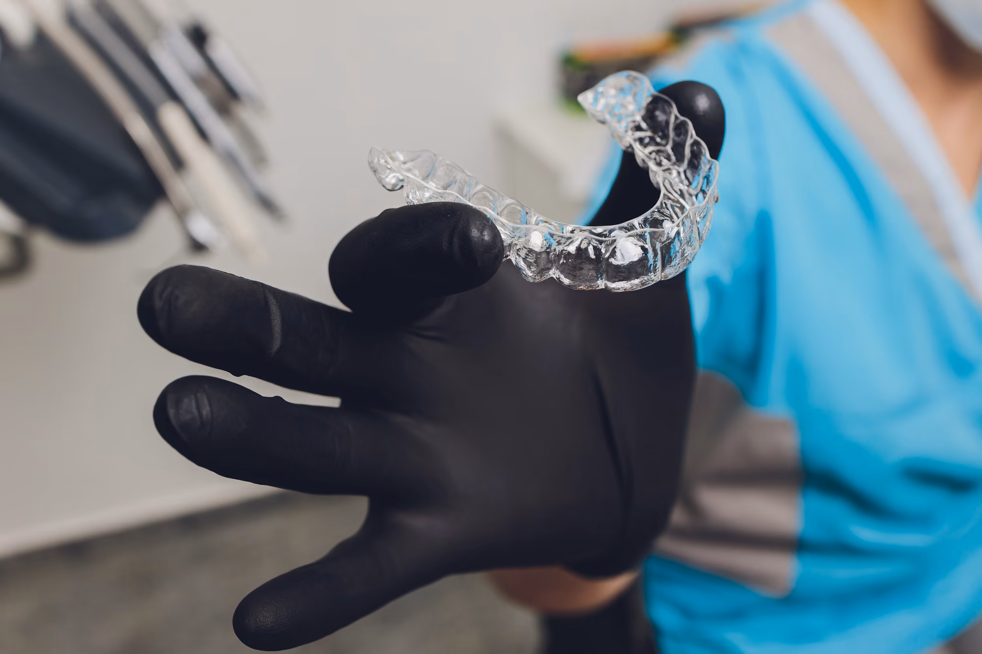 gloved hand holding an invisalign aligner