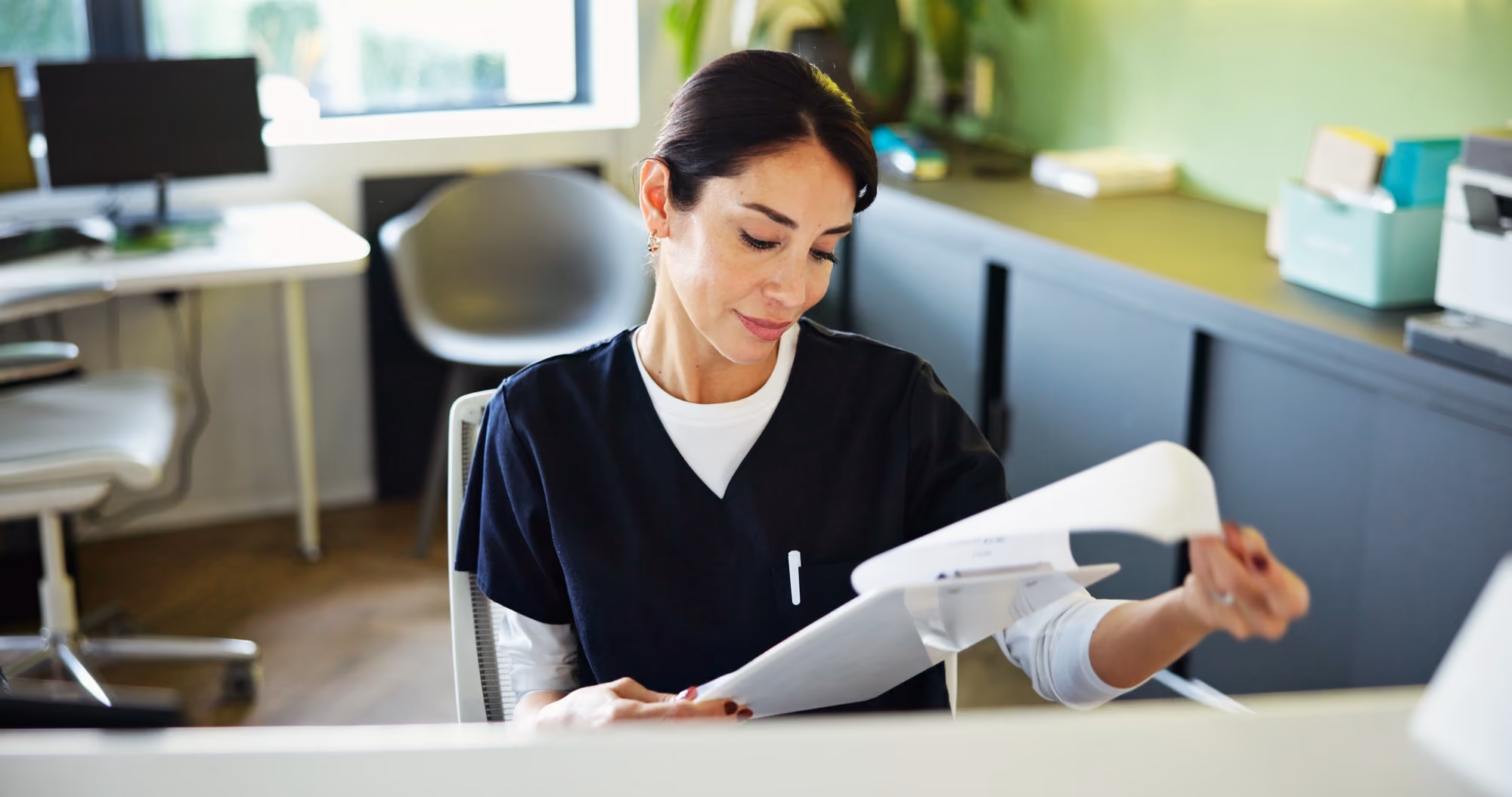 Dental professional reviewing patient records and notes in a dental office.