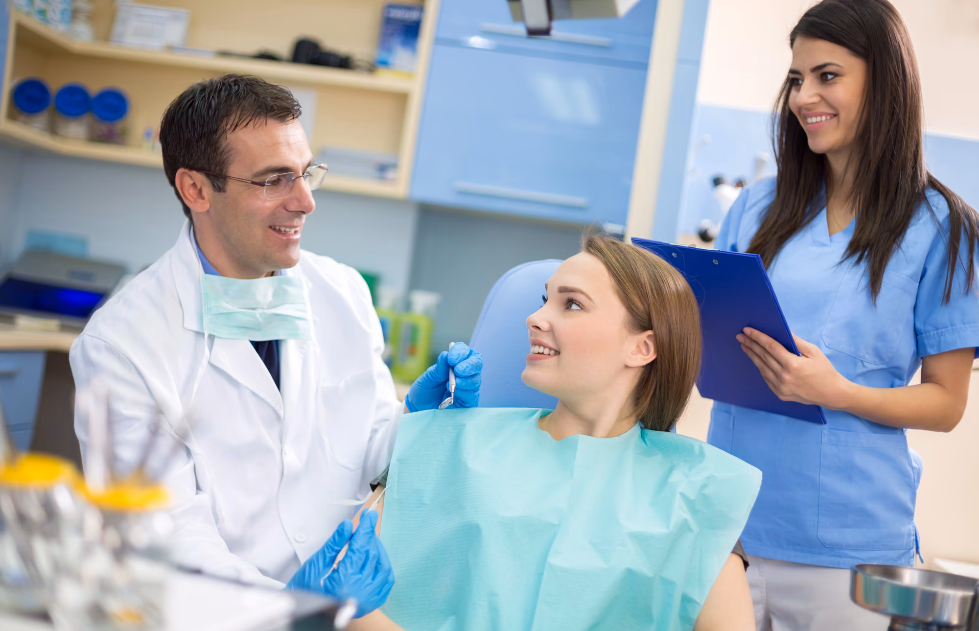 Dental team consulting with a smiling patient during a chairside appointment.
