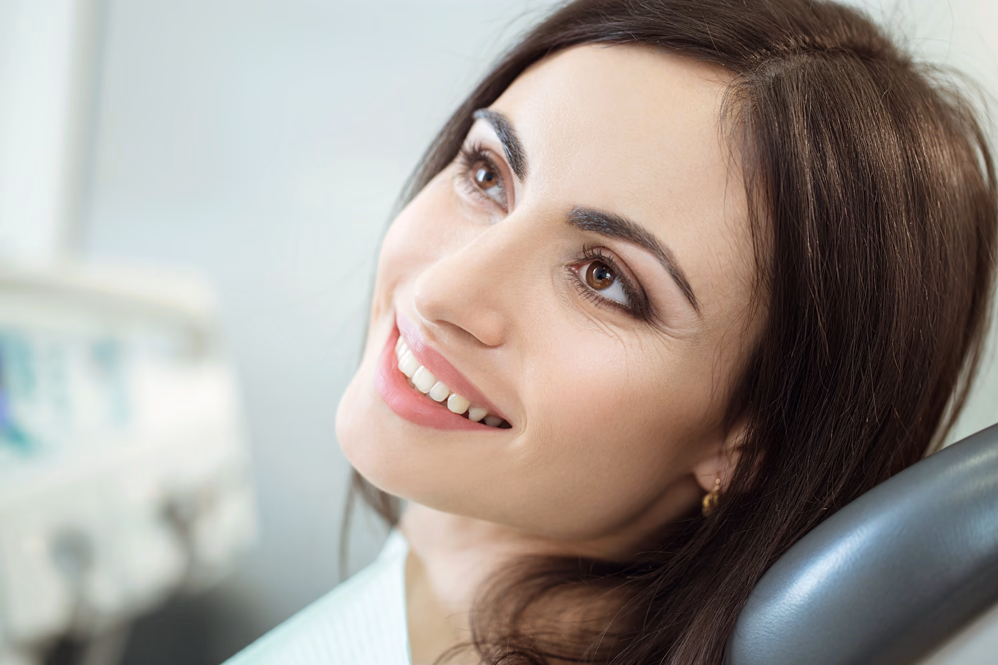 Female patient smiling while seated comfortably in a dental chair.