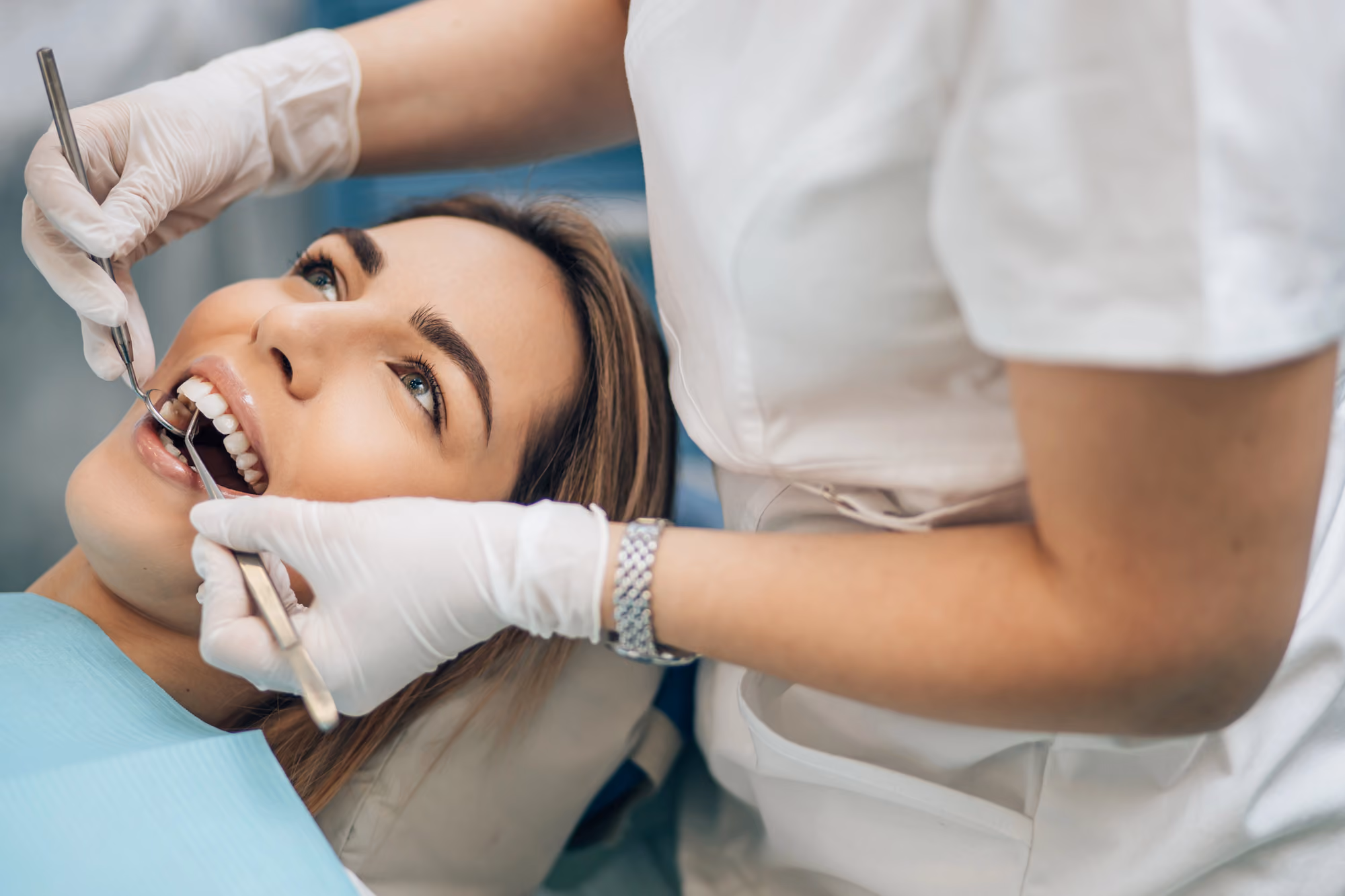 Dental professional performing a routine dental cleaning on a smiling patient.
